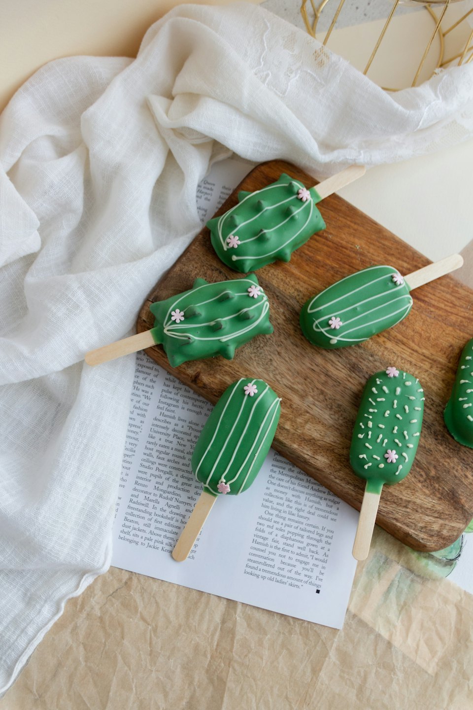Cactus cake pops arranged on a wooden board.