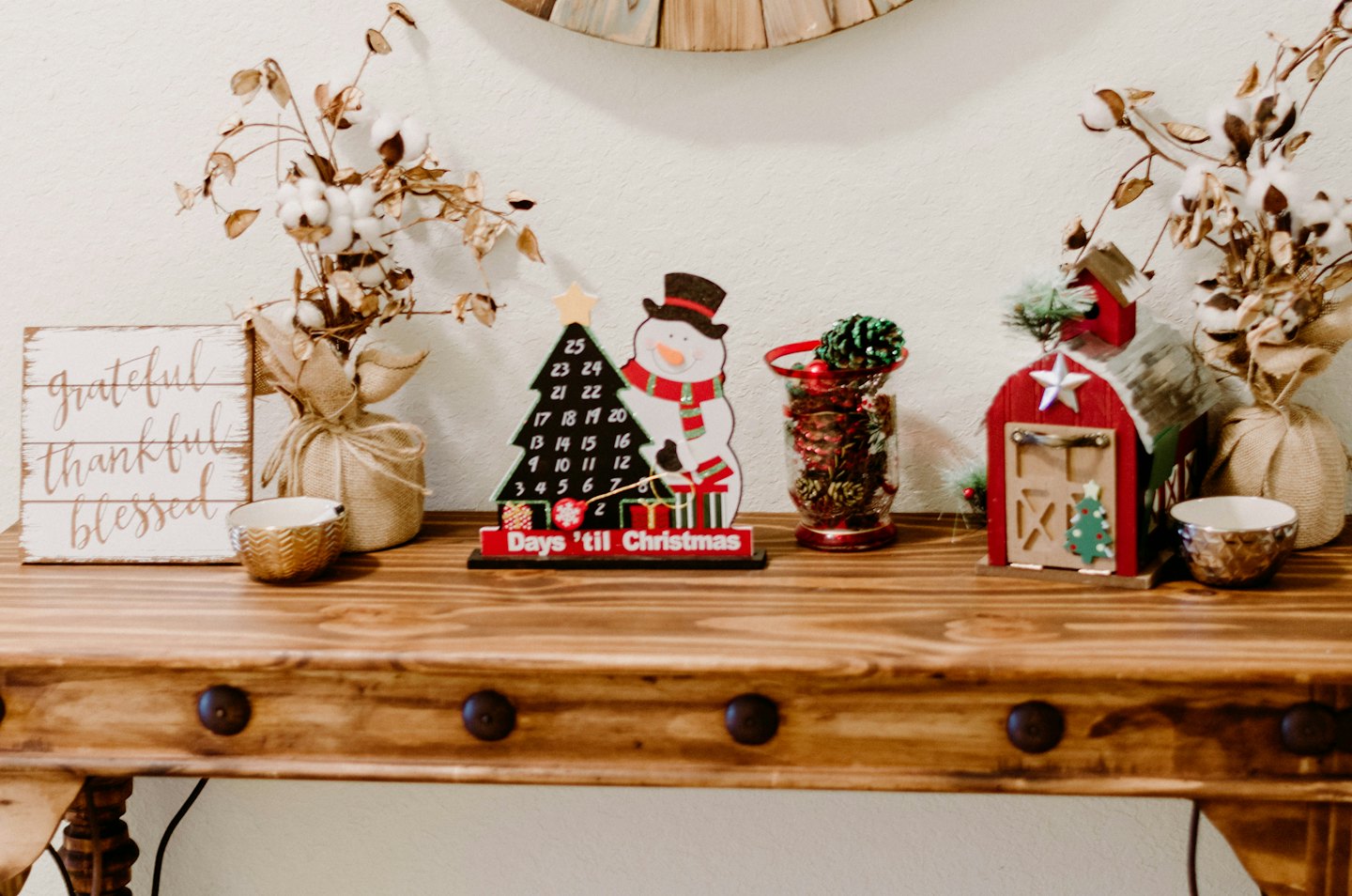 Christmas decorations and a wooden sign sit on a console table.